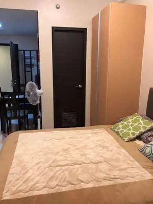 a bedroom with a bed and a black door with a fan at Ivy Condotels Unit -101Newport Boulevard in Manila