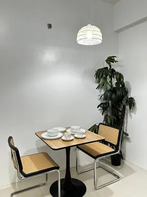 a table and chairs in a room with a plant at Tranquil Space Across Airport NAIA 3 in Manila