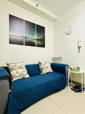 a blue couch in a room with a clock on the wall at New Oasis Staycation Shore 2 in Manila