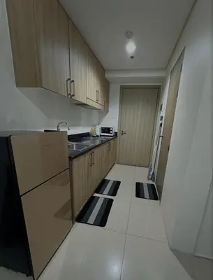 a kitchen with wooden cabinets and a counter top at 1BR Shore Residences near Mall Of Asia in Manila