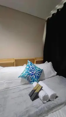 a bed with a blue umbrella and towels on it at Mall of Asia Garden view 2 Bedrooms 2 bathrooms in Manila