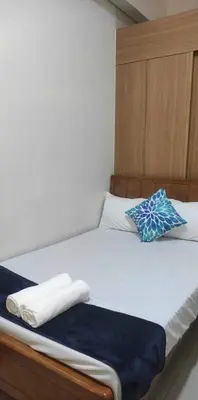 a bed with white sheets and blue pillows on it at Mall of Asia Garden view 2 Bedrooms 2 bathrooms in Manila