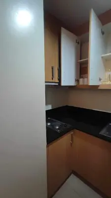 a kitchen with white cabinets and a black counter top at Mall of Asia Garden view 2 Bedrooms 2 bathrooms in Manila