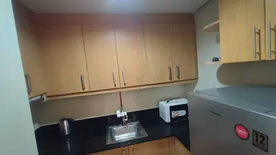 a small kitchen with wooden cabinets and a sink at Mall of Asia Garden view 2 Bedrooms 2 bathrooms in Manila