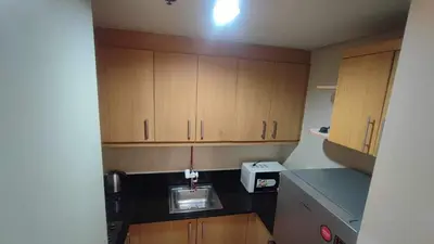 a small kitchen with wooden cabinets and a sink at Mall of Asia Garden view 2 Bedrooms 2 bathrooms in Manila