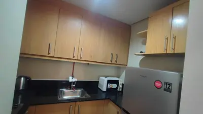 a kitchen with wooden cabinets and a stainless steel refrigerator at Mall of Asia Garden view 2 Bedrooms 2 bathrooms in Manila
