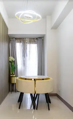 a dining room with a table and two yellow chairs at Stunning Suite with Balcony near MOA in Manila