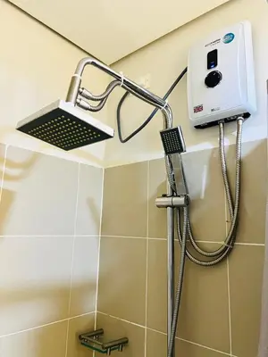 a shower with a shower head in a bathroom at Stunning Suite with Balcony near MOA in Manila