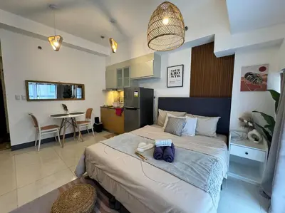 a bedroom with a large bed and a dining room at Studio Unit McKinley Hill Taguig cd21H in Manila