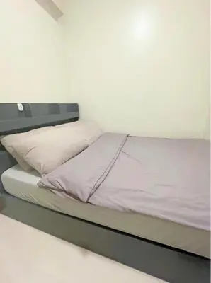 a bed in a room with a white wall at Callie's Cozy Home at Shore 3 Mall of Asia in Manila