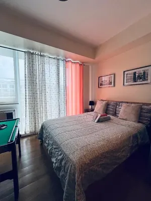 a bedroom with a bed with a table and a window at Spacious 1Bedroom Condotel Resort in Manila