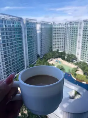 a person holding a cup of coffee in front of a city at Spacious 1Bedroom Condotel Resort in Manila
