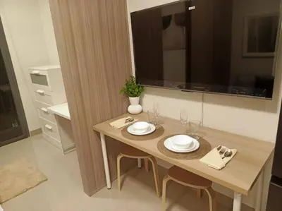 a wooden table with plates and glasses on it in a kitchen at Candid Suite by ARL in Manila
