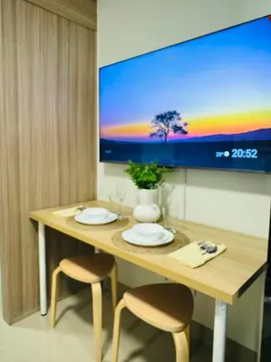 a table with two chairs and a tv on a wall at Candid Suite by ARL in Manila