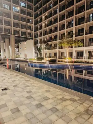 a large building with a swimming pool in front of it at Candid Suite by ARL in Manila