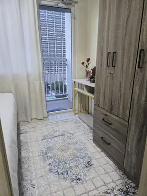 a bedroom with a large wooden cabinet and a window at Rhoydez Condotel Breeze Residence in Manila