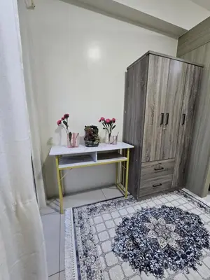 a room with a table and a cabinet with flowers on it at Rhoydez Condotel Breeze Residence in Manila