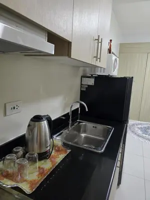 a kitchen counter with a sink and a tea kettle at Rhoydez Condotel Breeze Residence in Manila
