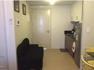 a kitchen with a black chair and a door at Ivy Condotels unit-150 Newport Boulevard near terminal 3 and all Airport in Manila