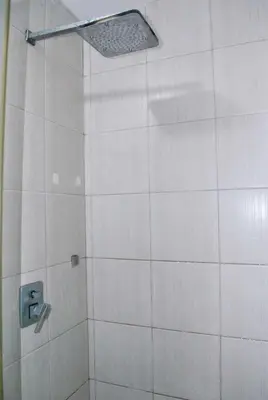 a white tiled shower with a shower head at Brianna's haven property rental in Manila