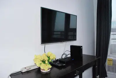 a desk with a computer and a tv on a wall at Brianna's haven property rental in Manila