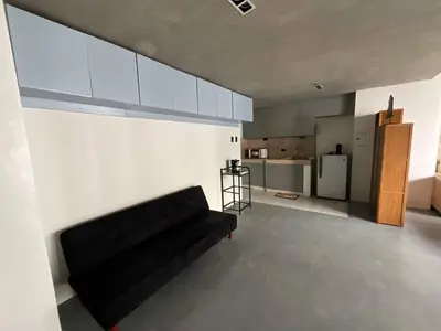 a living room with a black couch and a kitchen at 63 sqm Unit for GET TOGETHER at Poblacion, Makati with Private Parking in Manila