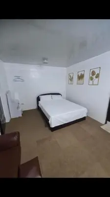 a bedroom with a bed in a white room at Js Guest House in Imus