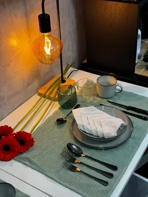a table with a plate and utensils on a table at Evergreen suite- 1 bed 1 sofa bed, light sync TV in Manila