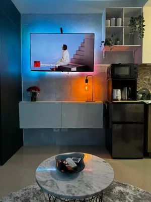 a kitchen with a tv on a wall with a table at Evergreen suite- 1 bed 1 sofa bed, light sync TV in Manila