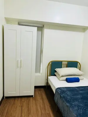 a bedroom with a white cabinet and a bed at FAIRLANE residences in Manila