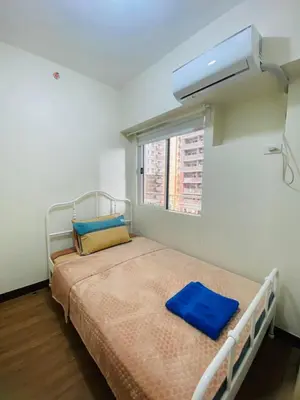 a small bedroom with a bed with a air conditioner at Fairlane Residences in Manila