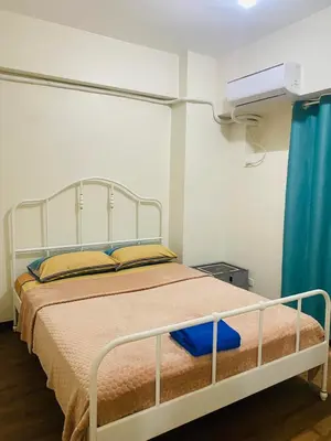 a bed in a small room with a blue curtain at Fairlane Residences in Manila
