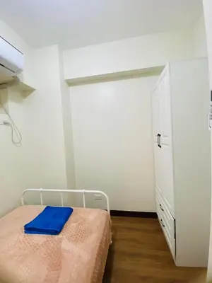 a bedroom with a bed and a white cabinet at Fairlane Residences in Manila