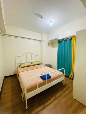 a bedroom with a bed and a blue curtain at Fairlane Residences in Manila