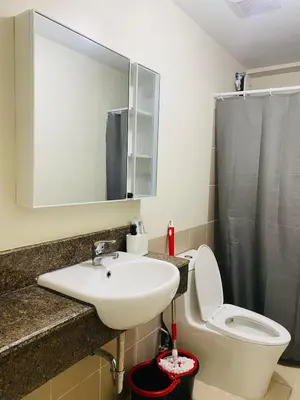 a bathroom with a sink and a toilet and a mirror at Fairlane Residences in Manila