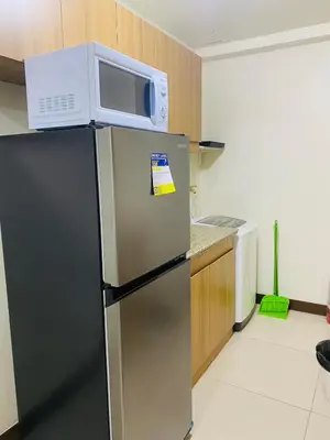 a refrigerator with a microwave on top of it at Fairlane Residences in Manila