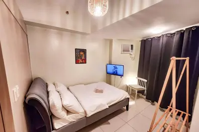 a small room with a bed and a television at Spacious Pool View 2br 2bath Apt in Makati in Manila