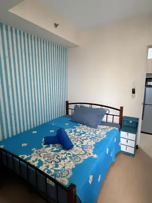 a bedroom with a bed with a blue comforter at Torre De Manila in Manila