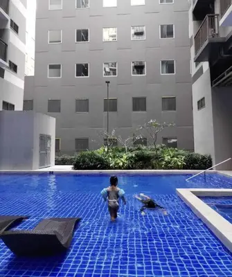 a person standing in a swimming pool next to a building at S Residences Two Beds Room Near MOA Pasay Manila in Manila