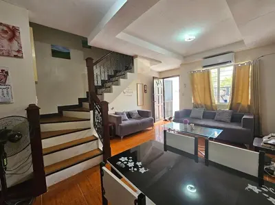 a living room with a couch and a staircase at Alohas House in Cupang