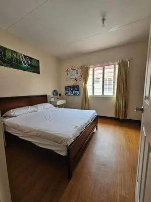 a bedroom with a large bed and a wooden floor at Alohas House in Cupang