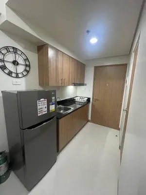 a kitchen with a refrigerator and a clock on the wall at Red Residences Chino Roces Makati in Manila