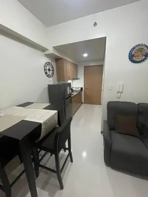 a living room with a table and a couch and a kitchen at Red Residences Chino Roces Makati in Manila