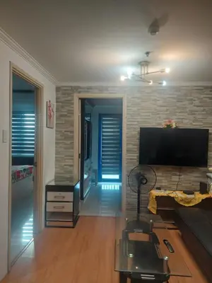 a living room with a television and a brick wall at 2BR SEA RESIDENCES By ELSIE D in Manila