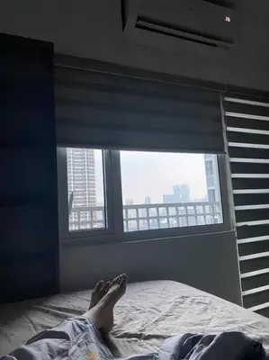 a person laying on a bed in front of a window at Casa Cintores Condo near PICC with FREE parking in Manila