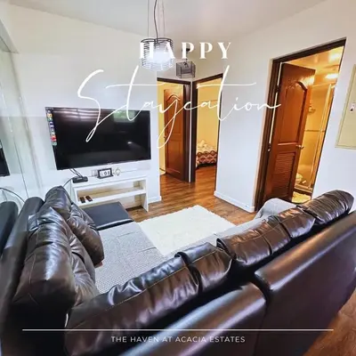 a living room with a leather couch and a television at The Haven at Acacia Estates in Manila