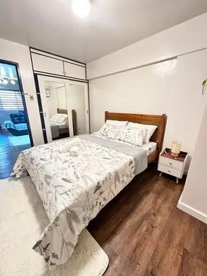 a bedroom with a large bed with a wooden floor at The Haven at Acacia Estates in Manila