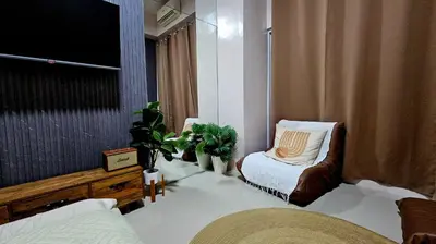 a room with a bed and a chair and a television at Uno - Condo Unit in SM Jazz Residences in Manila