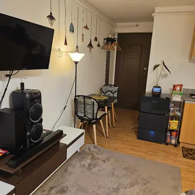a living room with a television and a table with chairs at Mench Staycation in Manila