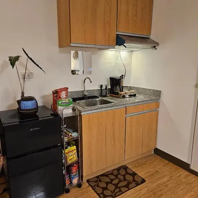 a kitchen with a sink and a black refrigerator at Mench Staycation in Manila